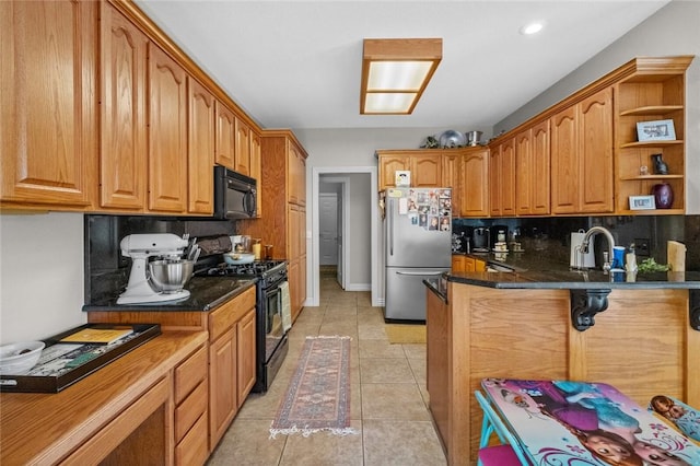 kitchen featuring a kitchen bar, sink, black appliances, light tile patterned floors, and backsplash