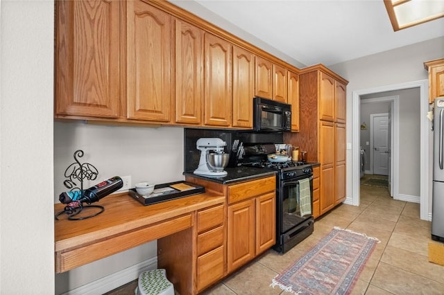 kitchen with light tile patterned floors, built in desk, and black appliances