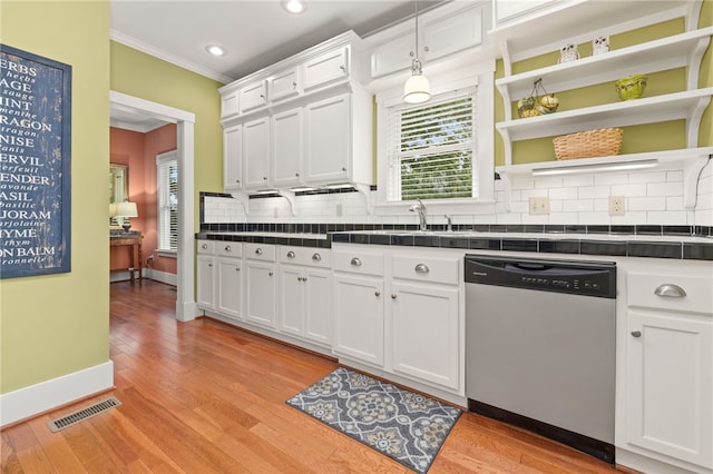 kitchen featuring a wealth of natural light, crown molding, decorative light fixtures, dishwasher, and white cabinetry