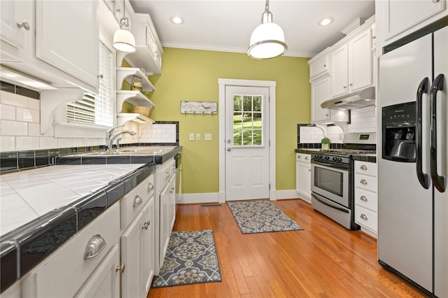 kitchen featuring white cabinetry, tile counters, stainless steel gas range oven, and fridge with ice dispenser