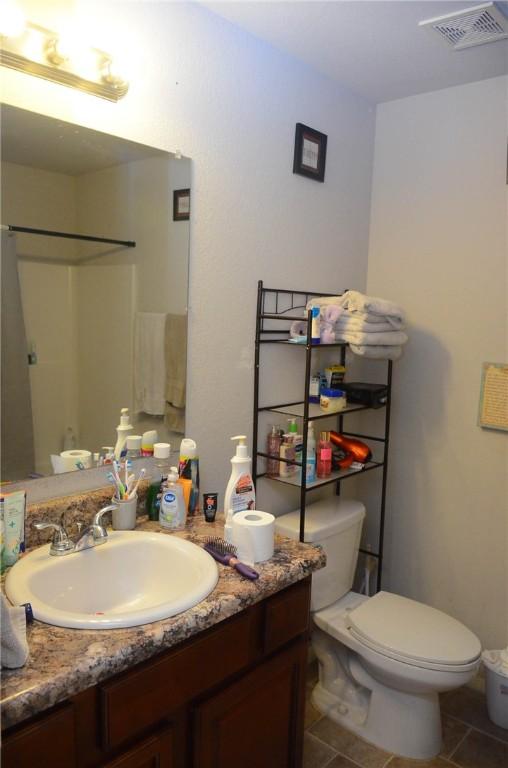 bathroom featuring toilet, tile floors, and large vanity