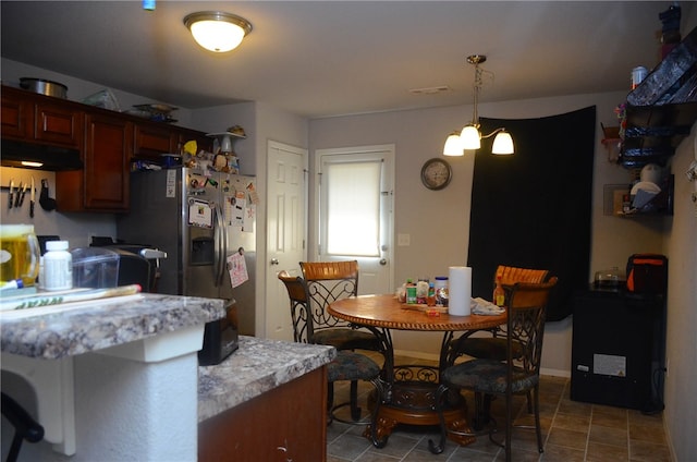 kitchen featuring hanging light fixtures, dark tile floors, and stainless steel fridge