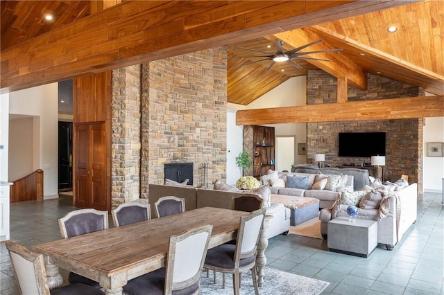 tiled dining space featuring wood ceiling, a stone fireplace, ceiling fan, high vaulted ceiling, and beam ceiling