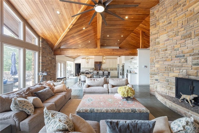 tiled living room with high vaulted ceiling, a stone fireplace, wood ceiling, and ceiling fan with notable chandelier