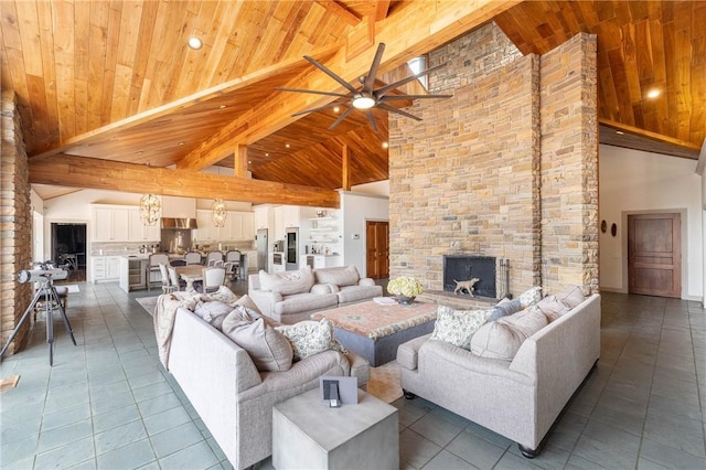 living room with high vaulted ceiling, tile patterned floors, a stone fireplace, and ceiling fan with notable chandelier