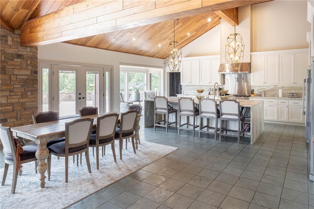 dining space with a notable chandelier, beam ceiling, wood ceiling, high vaulted ceiling, and french doors