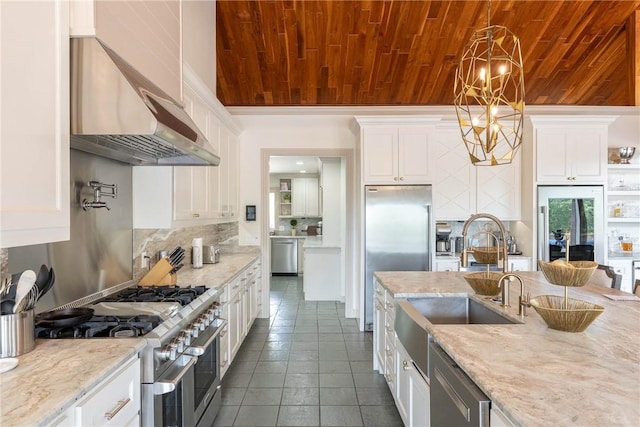 kitchen featuring pendant lighting, white cabinetry, high end appliances, ventilation hood, and light stone counters