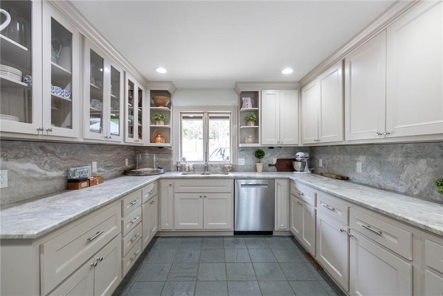 kitchen with stainless steel dishwasher, sink, dark tile patterned floors, light stone countertops, and white cabinets