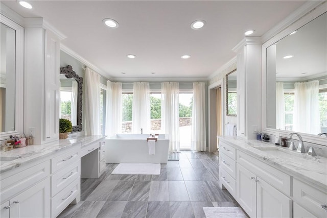 bathroom with plenty of natural light, vanity, ornamental molding, and a bathing tub