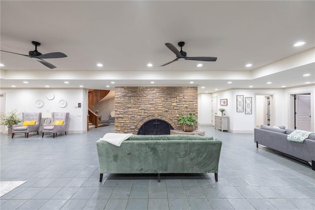 living room with ceiling fan and a stone fireplace