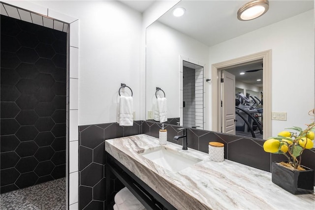 bathroom featuring vanity, tile walls, and a tile shower