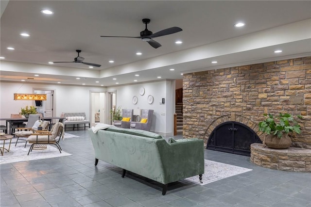 living room with ceiling fan and a stone fireplace