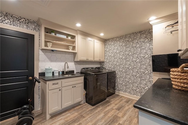 kitchen with washer and dryer, white cabinetry, decorative backsplash, sink, and light hardwood / wood-style floors