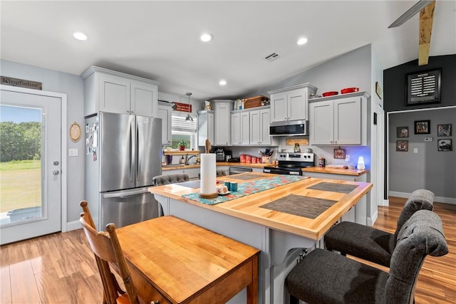 kitchen featuring lofted ceiling, stainless steel appliances, wooden counters, and light hardwood / wood-style flooring