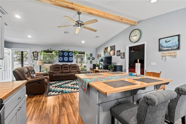 dining area with vaulted ceiling with beams, ceiling fan, and light wood-type flooring