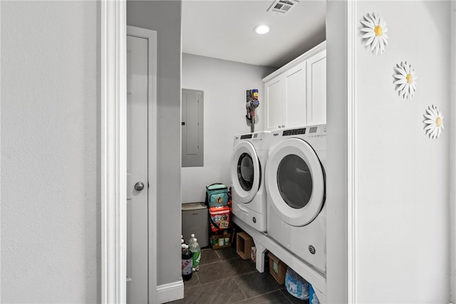 washroom with cabinets, dark tile patterned flooring, washing machine and clothes dryer, and electric panel