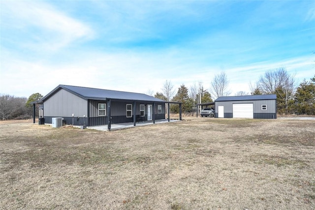 back of property with a garage, an outdoor structure, and a lawn