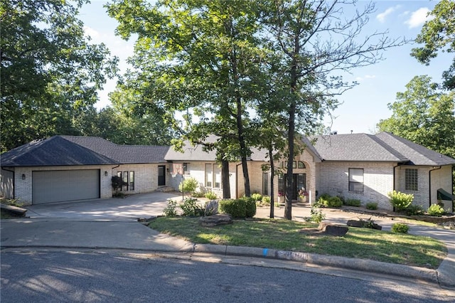 ranch-style home with brick siding, an attached garage, concrete driveway, and a shingled roof