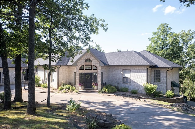 view of front of property featuring brick siding and a shingled roof
