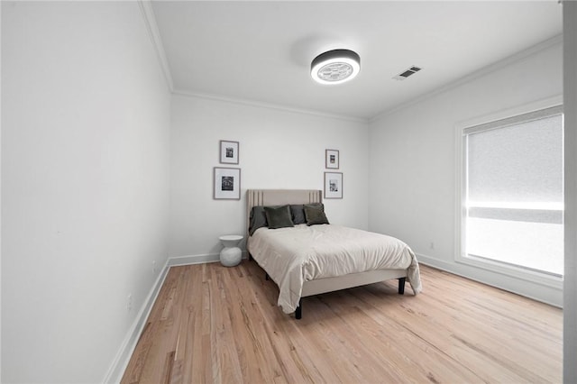 bedroom with ornamental molding, light wood-style floors, and baseboards
