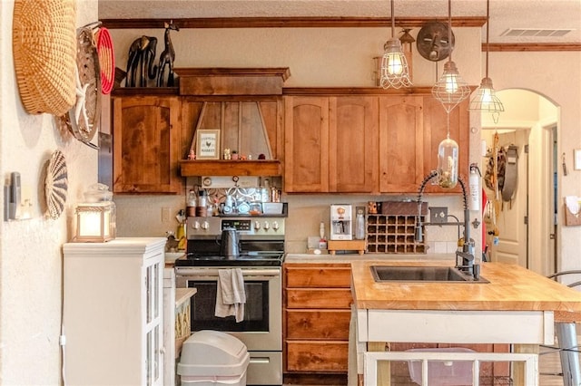 kitchen featuring sink, hanging light fixtures, wooden counters, crown molding, and stainless steel range with electric stovetop