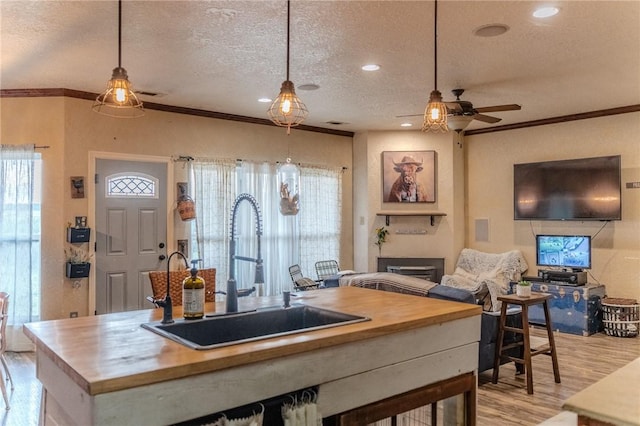 kitchen featuring sink, wooden counters, a textured ceiling, and light wood-type flooring