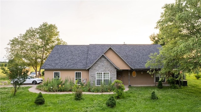 view of front of house featuring stone siding, a shingled roof, a front lawn, and stucco siding