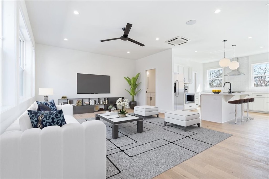 living room featuring light wood-type flooring, ceiling fan, and sink