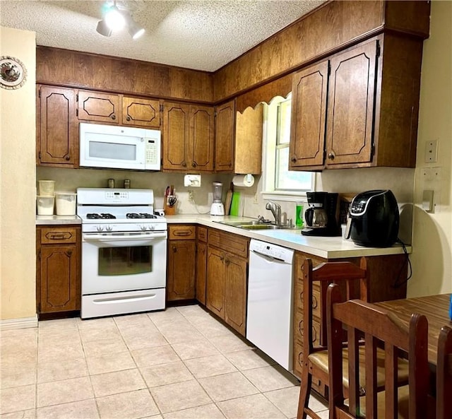 kitchen featuring a textured ceiling, light tile patterned flooring, sink, and white appliances