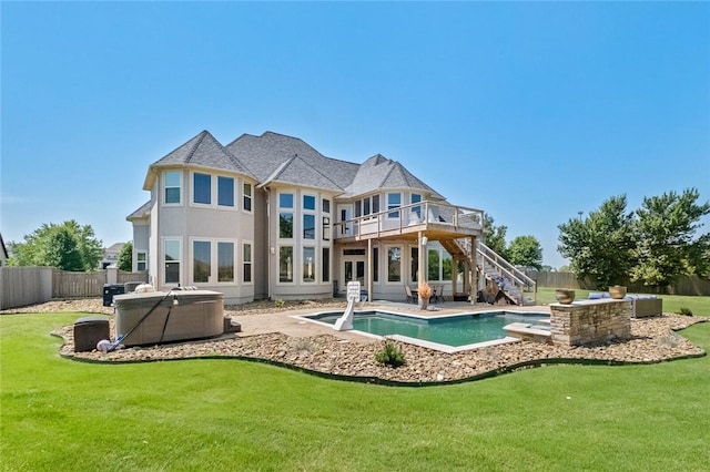 rear view of house with a yard, a patio, a wooden deck, and a hot tub