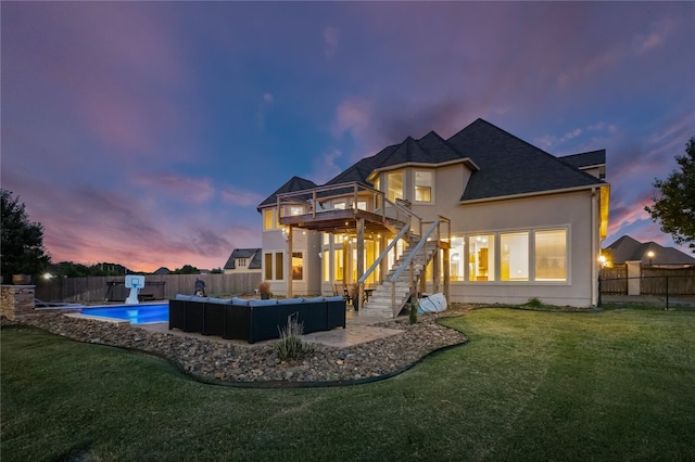 back house at dusk with a fenced in pool, an outdoor living space, a yard, and a balcony