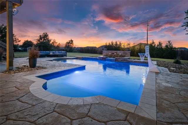 pool at dusk featuring a patio area, pool water feature, a hot tub, and an outdoor living space