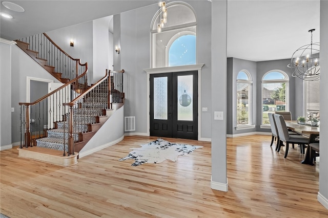 entrance foyer featuring french doors, light wood-type flooring, and an inviting chandelier