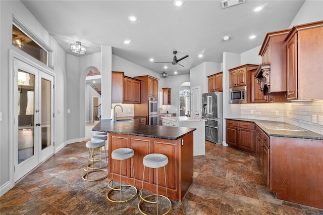 kitchen with kitchen peninsula, a kitchen breakfast bar, tasteful backsplash, stainless steel appliances, and ceiling fan