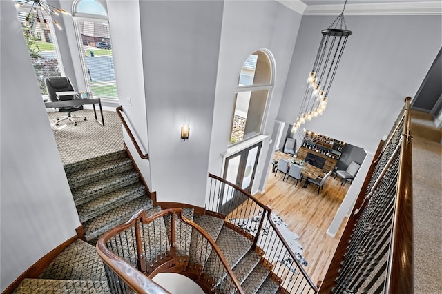 staircase featuring ornamental molding, a high ceiling, and an inviting chandelier