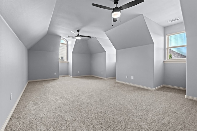 additional living space featuring ceiling fan, plenty of natural light, light carpet, and lofted ceiling