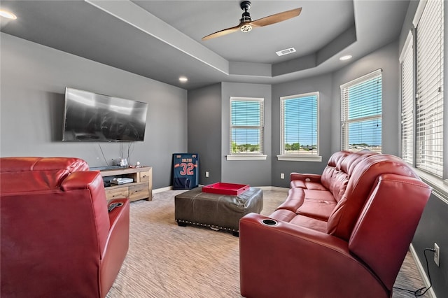 cinema room featuring ceiling fan, light colored carpet, and a tray ceiling