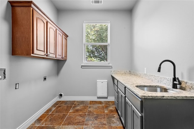 clothes washing area with cabinets, electric dryer hookup, and sink