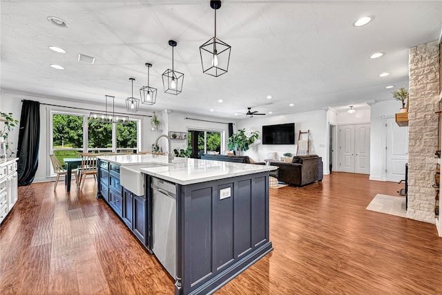 kitchen with sink, an island with sink, hardwood / wood-style floors, decorative light fixtures, and stainless steel dishwasher