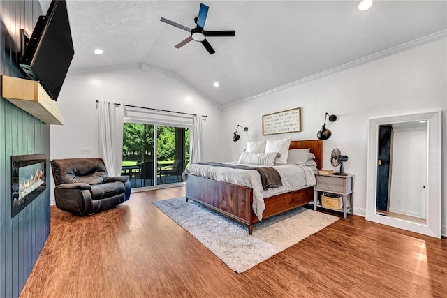 bedroom with access to exterior, wood finished floors, ornamental molding, and a large fireplace
