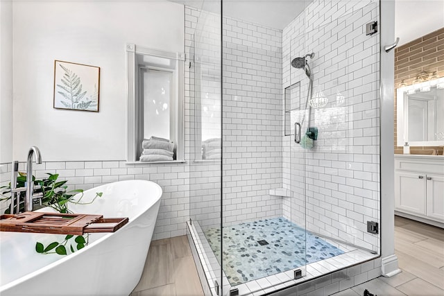 bathroom featuring independent shower and bath, vanity, tile walls, and hardwood / wood-style floors