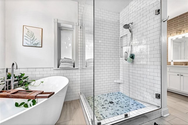 bathroom featuring a freestanding bath, vanity, a stall shower, and tile walls