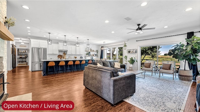 living room featuring ceiling fan, dark hardwood / wood-style floors, and a fireplace