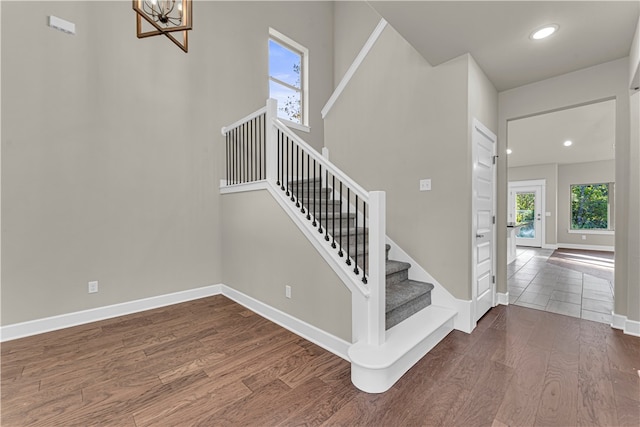 staircase with a chandelier and hardwood / wood-style flooring