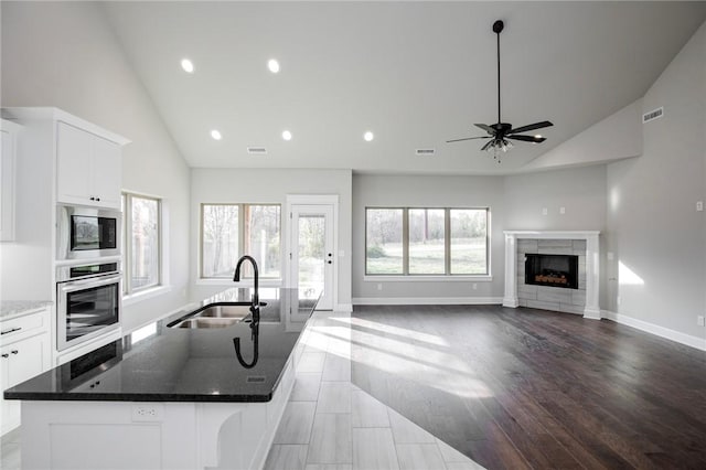 kitchen with ceiling fan, a sink, high vaulted ceiling, stainless steel appliances, and visible vents