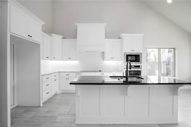 kitchen featuring a sink, built in microwave, backsplash, and white cabinetry