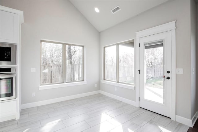 doorway with baseboards, visible vents, and high vaulted ceiling