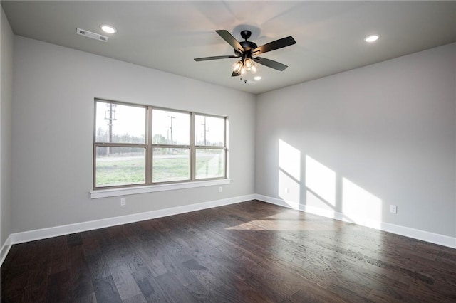 spare room with baseboards, dark wood-style flooring, and visible vents