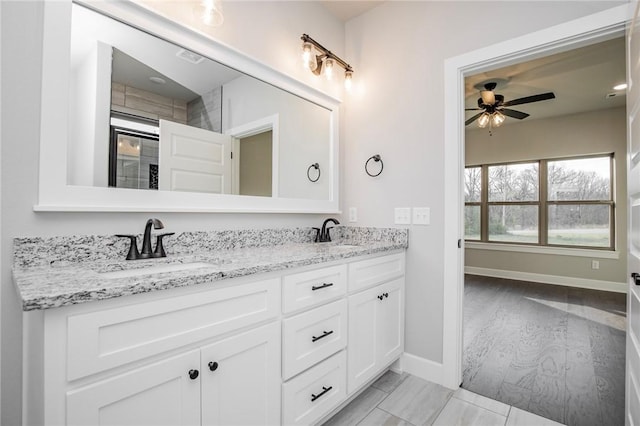 full bath with double vanity, a sink, baseboards, and ceiling fan