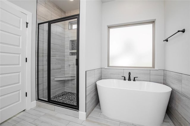 bathroom featuring a freestanding tub, plenty of natural light, a shower stall, and marble finish floor